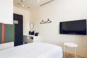 a bedroom with a bed and a flat screen tv at CHECK Inn Express New Taipei Tamsui in Tamsui