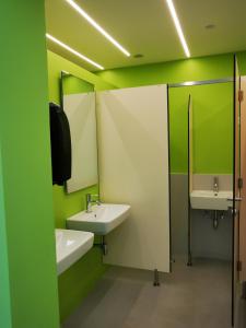 - une salle de bains verte et blanche avec deux lavabos et des miroirs dans l'établissement Krasen Kras 104 resort, à Komen