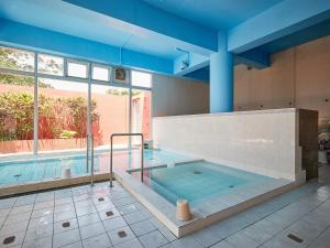 a large indoor swimming pool with a large window at Hotel Murasakimura in Yomitan