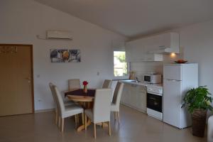 a kitchen with a table and a white refrigerator at Apartment Greta,50 METERS TO THE BEACH in Banjole