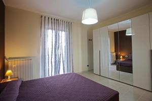 1 dormitorio con cama morada y espejo grande en La Dimora Accommodation, en Bari