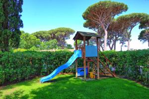 um parque infantil com um escorrega na relva em Villa Dolce Vita by PosarelliVillas em Punta Ala