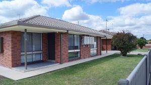 a red brick house with a grass yard at Maude St Apartments in Shepparton