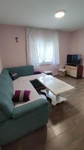 ein Wohnzimmer mit einem grünen Sofa und einem Tisch in der Unterkunft Casa Del Pellegrino M&A - Ostojići in Međugorje