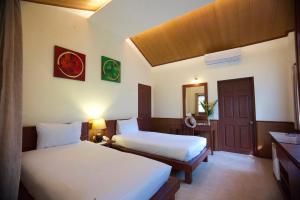 a hotel room with two beds and a mirror at Pinnacle Samui Resort in Mae Nam
