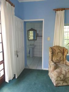 a bathroom with a toilet and a chair and a sink at Springfontein Guesthouse in Springfontein