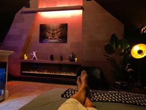 een persoon die op een bed ligt in een kamer met een open haard bij LoCo Paradiso - Two kingsize beds, outdoor terrace, DJ booth, bar, cinema, bathtub, kitchen, airco in Antwerpen
