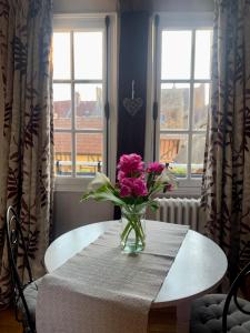 a vase of pink flowers sitting on a table in front of windows at La petite duchesse in Vernon