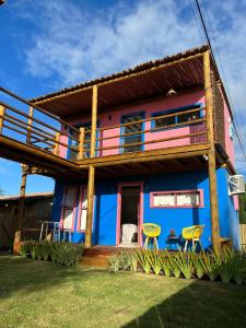 Casa colorida con balcón y 2 sillas en EcoFlats Caraiva en Caraíva