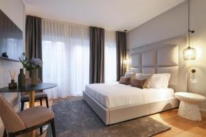 a bedroom with a bed and a table and a chair at PRESTIGE BOUTIQUE APARTHOTEL - Piazza Duomo View in Milan