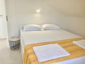 ein weißes Bett mit zwei Kissen auf einem Zimmer in der Unterkunft Apartment Villa Sunshine in Sutivan