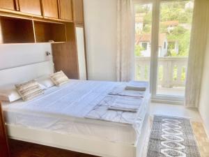 ein weißes Bett in einem Zimmer mit Fenster in der Unterkunft Apartment Villa Sunshine in Sutivan