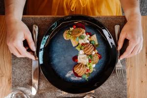 a person holding a plate of food on a table at Klosterhof – Alpine Hideaway & Spa in Bad Reichenhall