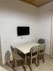 a dining room table with chairs and a tv on a wall at Jons Apartment in Gjirokastër