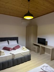 a bedroom with two beds and a desk with a television at Jons Apartment in Gjirokastër