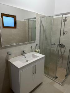 a bathroom with a white sink and a shower at Jons Apartment in Gjirokastër