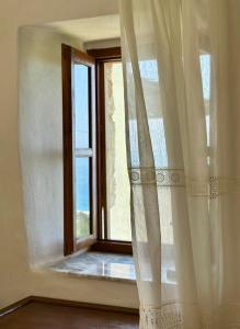 Amphora Guesthouse & Apartments في هيماري: نافذة مع ستائر بيضاء في الغرفة