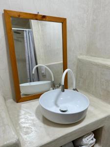 La salle de bains est pourvue d'un lavabo blanc et d'un miroir. dans l'établissement Amphora Guesthouse & Apartments, à Himarë