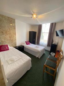 een hotelkamer met 2 bedden en een stoel bij OYO Carlton Court Hotel in Eastbourne