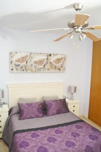 a bedroom with a purple bed and a ceiling fan at 1ra Linea Playa Magic World Luxury Apartament PP3 Pet in Oropesa del Mar