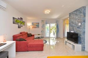a living room with a red couch and a tv at Apartments Mala Vala 925 - adapted in Fažana