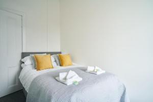 a white bed with yellow pillows and towels on it at Meadow Apartment in Dumbarton