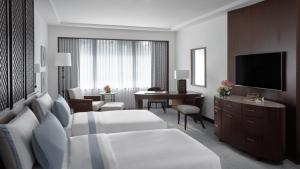 a hotel room with a bed and a desk and a television at The Peninsula Manila in Manila