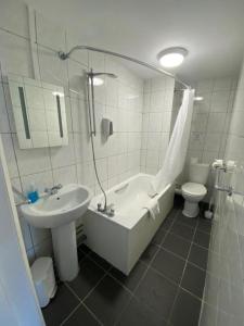 y baño con bañera, lavabo y aseo. en OYO Carlton Court Hotel en Eastbourne