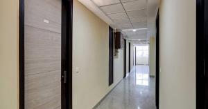 a hallway of an office with white walls and wooden doors at Flagship Mt Corporate Suites Pari Chowk Near Pvr Ansal Plaza Greater Noida in Greater Noida