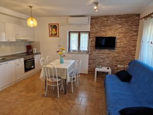eine Küche und ein Wohnzimmer mit einem Tisch und einem blauen Sofa in der Unterkunft Apartman Aja in Kaštelir