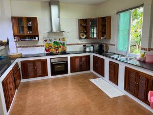 cocina grande con armarios de madera y fregadero en Daras house, en Ban Klam