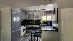 una cucina con piano di lavoro nero e lavastoviglie di La Tissonnière Oasis d Exception entre Mer Alpilles et Luberon Spa et Piscine à 10 min d Aix en Provence a Saint-Estève-Janson