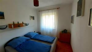 1 dormitorio con 2 camas azules y ventana en Szalakóta Ház, en Balatongyörök