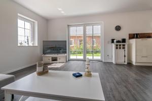 a living room with a table and a kitchen at Landhaus Seewind mit Sauna in Dornum