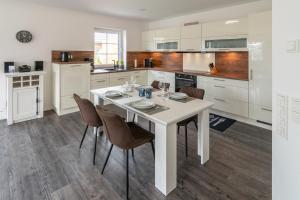 Una cocina blanca con una mesa y sillas blancas. en Landhaus Seewind mit Sauna, en Dornum