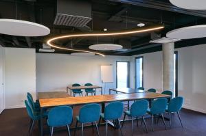 una sala de conferencias con una mesa de madera y sillas azules en Hôtel Akena Chauray-Niort, en Chauray