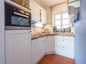 eine Küche mit weißen Schränken und einer schwarzen Mikrowelle in der Unterkunft Feriendorf Rugana - Komfort Appartement mit 2 Schlafzimmern und Terrasse C48 in Dranske