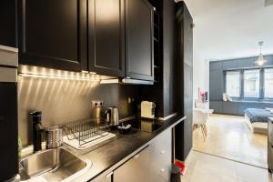 a kitchen with black cabinets and a sink at Bright studio apartment with a gorgeus Parliament in Budapest