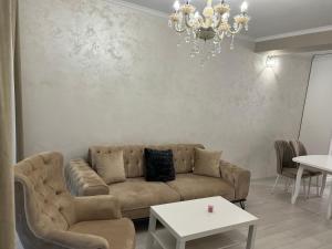 a living room with a couch and a chandelier at DELUXE APARTAMENTS DARIS in Kazanlŭk
