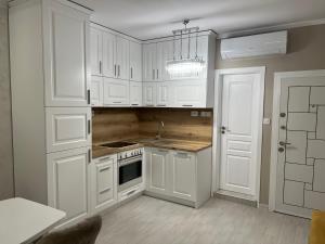 uma cozinha com armários brancos e um lustre em DELUXE APARTAMENTS DARIS em Kazanlŭk