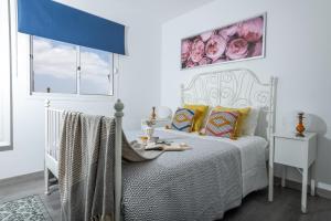 - une chambre avec un lit blanc et un rideau bleu dans l'établissement Casa Virginia Corralejo by iRent Fuerteventura, à Corralejo