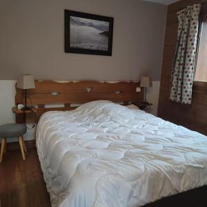 un letto bianco in una camera da letto con una foto sul muro di Appartement 4 pers avec piscine commune Carroz d'Araches a Les Carroz d'Araches