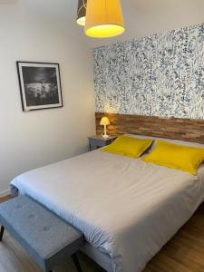 a bedroom with a large white bed with yellow pillows at LE CLOS DE LA VINIERE in Jard-sur-Mer