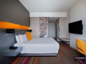 Mercure Bangkok Siam في بانكوك: غرفة فندق بسرير ابيض وتلفزيون