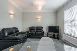 sala de estar con 2 sillas de cuero y TV en Gillian House - Charming Broadstairs apartment, en Kent