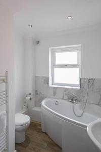 baño con bañera, aseo y ventana en Gillian House - Charming Broadstairs apartment en Kent