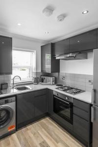 cocina con armarios negros y horno con fogones en Gillian House - Charming Broadstairs apartment, en Kent