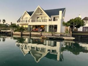 a house with a reflection in the water at St Francis Bay House On The Canal in St Francis Bay