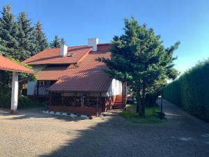 una casa con techo rojo y un árbol en Willa 250 M z basenem, jacuzzi, ogrodem , tarasem oraz 2 hektary sadu , kominek i inne atrakcje 