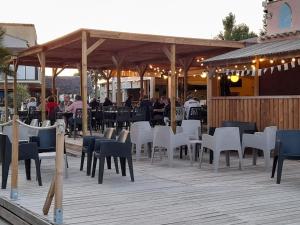 a patio with white chairs and tables and a restaurant at Le Cosy, mobil-home 4-6 personnes au camping les Sables du Midi à Valras-Plage in Valras-Plage
